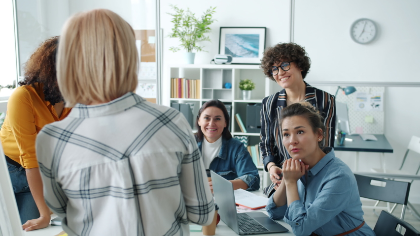 Creative team of female employees are talking to mature woman making presentation in glass wall office discussing project. People and teamwork concept. Royalty-Free Stock Footage #1069109575