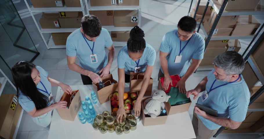 Top view of successful multi-ethnic corporate team volunteers collecting free food and supplies in carton boxes collaborating at workshop. Royalty-Free Stock Footage #1069110805