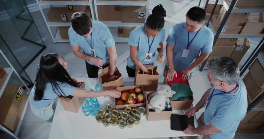 Top view of successful multi-ethnic corporate team volunteers collecting free food and supplies in carton boxes collaborating at workshop. | Shutterstock HD Video #1069110805