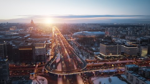 Aerial sunset panorama of Moscow highway with a lot of traffic in winter. Camera showing beautiful city and wide road with junctions and cars driving in the evening lights.