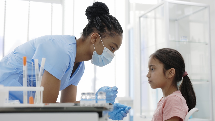 Crop view of medical female nurse in protectivemask and gloves taking swab from nose of little girl in hospital. Concept of PCR diagnostic method, rapid covid test. Royalty-Free Stock Footage #1069112521