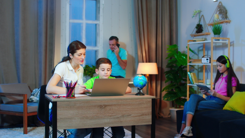 Big charismatic family dad and man helping the son to the his school project while the sister sitting on the living room sofa. Shot on ARRI Alexa
