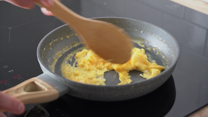 Scrambled eggs, omelette. Cooking breakfast with pan-fried eggs. Preparing food on pan. Mixing egg in pan with wooden spatula. Morning daily routine of weekend. Texture of omelet. Keto ketogenic diet Royalty-Free Stock Footage #1069114699