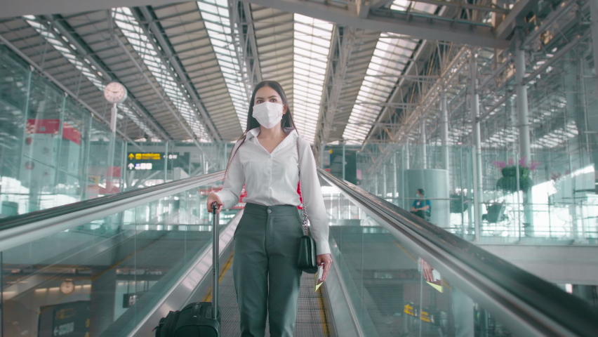 A business woman is wearing protective mask in International airport, travel under Covid-19 pandemic, safety travels, social distancing protocol, New normal travel concept Royalty-Free Stock Footage #1069114990