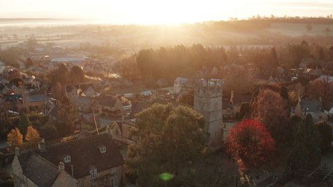 Aerial drone video of Typical English village and beautiful British countryside scenery in The Cotswolds showing a rural church at sunrise in morning sun at Longborough, Gloucestershire, England, UK