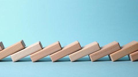Domino effect, row of wooden domino falling down with blue background.