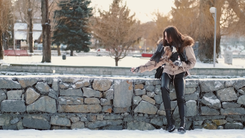 Beautiful woman walk with york terrier in the park. Weekend, winter.