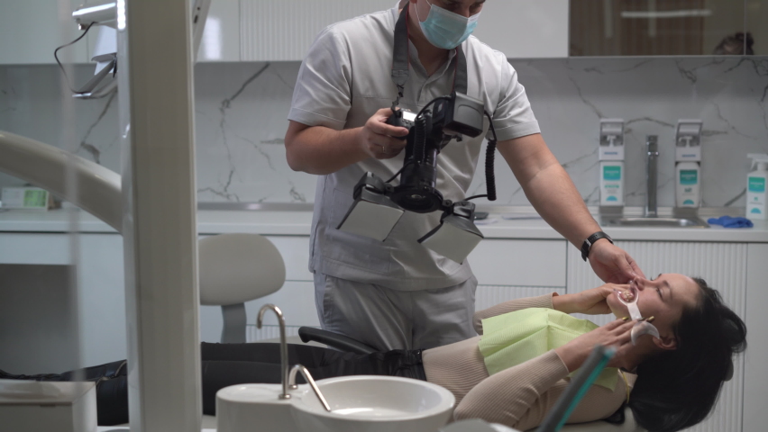 young man dentist taking off his mouth, his work on the teeth of a patient in the dental office. photographs the patient s teeth. Royalty-Free Stock Footage #1069133110