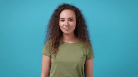 Excited cheerful young african american woman 20s years old in casual green khaki t-shirt posing isolated on blue background studio. People emotions lifestyle concept. Showing thumbs up like gesture