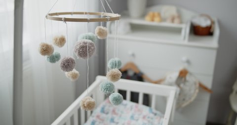 Handmade baby nursery mobile hanging spinning above crib in child bedroom