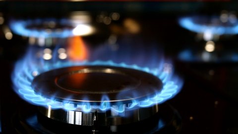 Process of burning and appearing blue flame gas methane or propane on kitchen gas stove. Kitchen burner switching. Natural gas inflammation. Selective focus.