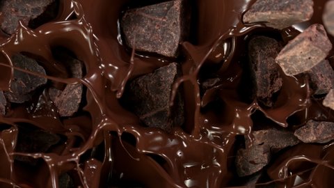 Super Slow Motion Shot of Raw Chocolate Chunks Falling into Melted Chocolate at 1000 fps.