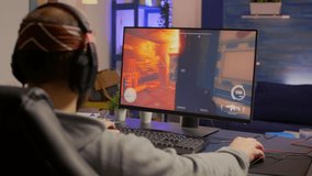 Professional player with headphones performing first person shooter video game with modern graphics at virtual championship. Online streaming cyber using technology network wireless