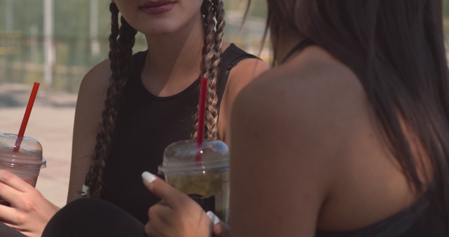 Two girls chatting in the park on a sunny day and drinking smoothie | Shutterstock HD Video #1069148746
