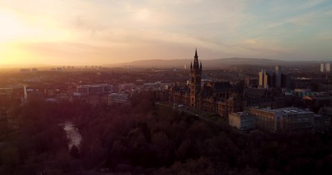Flying at sunset over the Kelvingrove park in Glasgow, Scotland towards the Gilbert Scott tower at Glasgow University.