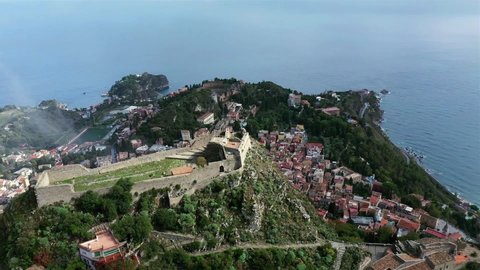 Drone shot of castle in Taormina, Sicily with ancient theatre in the background.