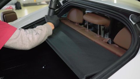 Auto detailing, Working with a vacuum cleaner, cleans the trunk of a car