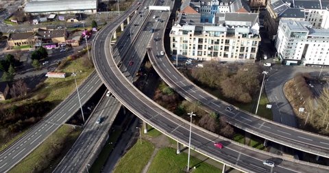 Aerial drone shot reveals spectacular elevated highway and convergence of roads, bridges, viaducts in Glasgow at sunset, transportation and infrastructure development in urban Scotland, UK