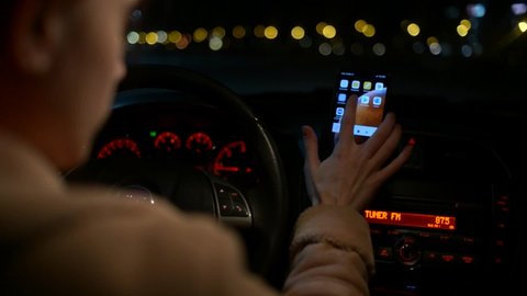WROCLAW, POLAND - MARCH 11, 2021: Night Driver Woman opens Google Map app On Mobile Phone in a Car