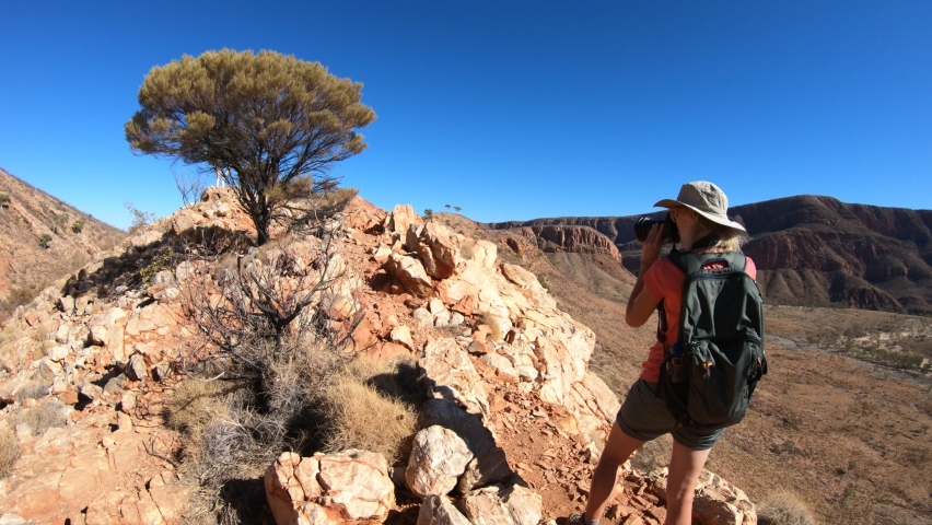 Woman photographer enjoying Mount Sonder and Gosses Bluff crater at halfway point in Larapinta Trail, Ormiston Pound Walk. Northern Territory, Australia in West MacDonnell Ranges a popular destination