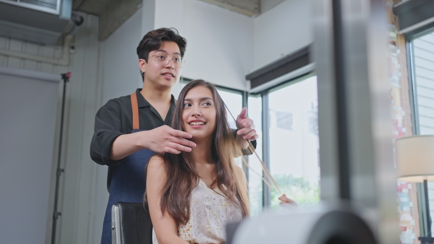 Asian professional hairdresser male giving a beauty salon service and treatment to young beautiful customer. Expert Stylist male recommend woman for maintain hair color in beauty salon or barber shop. | Shutterstock HD Video #1069167526