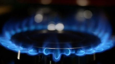 Process of burning and appearing blue flame of gas methane or propane on kitchen gas stove. Kitchen burner switching. Natural gas inflammation. Selective focus. Slow motion. Close-up.