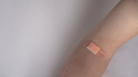 Male adult taking off medical band aid from elbow bend close up