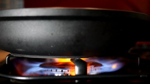 Process of burning and appearing blue flame gas methane, propane on kitchen gas stove. Kitchen burner switching. Natural gas inflammation. Selective focus. Slow motion. Close-up.