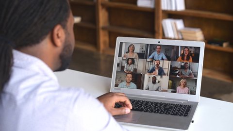 Close-up of African American man with dreadlocks using app for distance video communication with coworkers, friends, meeting online, looking and waving at laptop desktop with people profiles