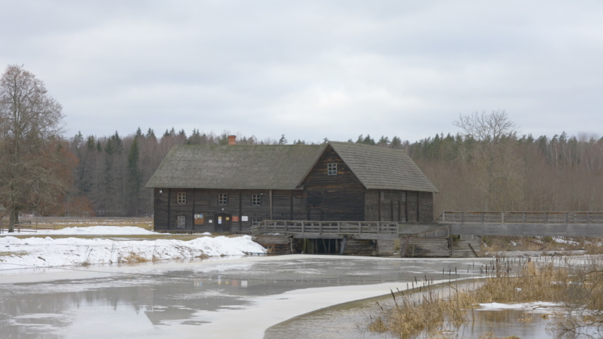 The thick white snow on the side of the lake with the wooden cabin house on the center in Estonia