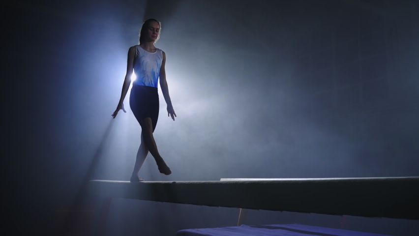 training of young female gymnast on balance beam in sportive hall, preparing to competition and Olympic games, artistic gymnastics