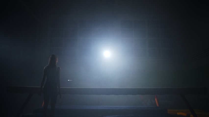 young sporty girl is performing on balance beam on junior artistic gymnastics competition, slow motion shot, teen female gymnast