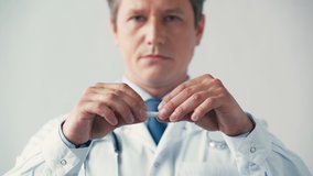 selective focus of doctor in white coat breaking cigarette on grey