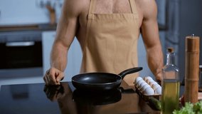 cropped view of shirtless man in apron frying chicken egg
