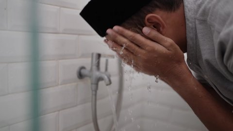 portrait of young Muslim man perform ablution wudhu before prayer at home