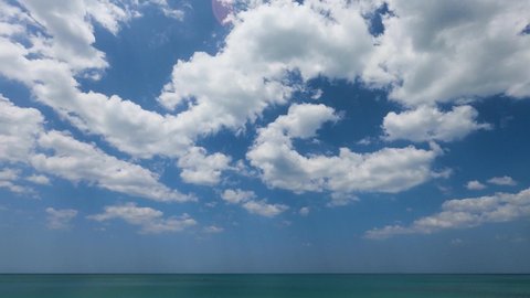 wonderful nature of clouds moving in the blue sky at green ocean water on a summer sunny day. sunlight reflected on the seawater surface. clouds traveling over the wide space of spring clear sky. 
