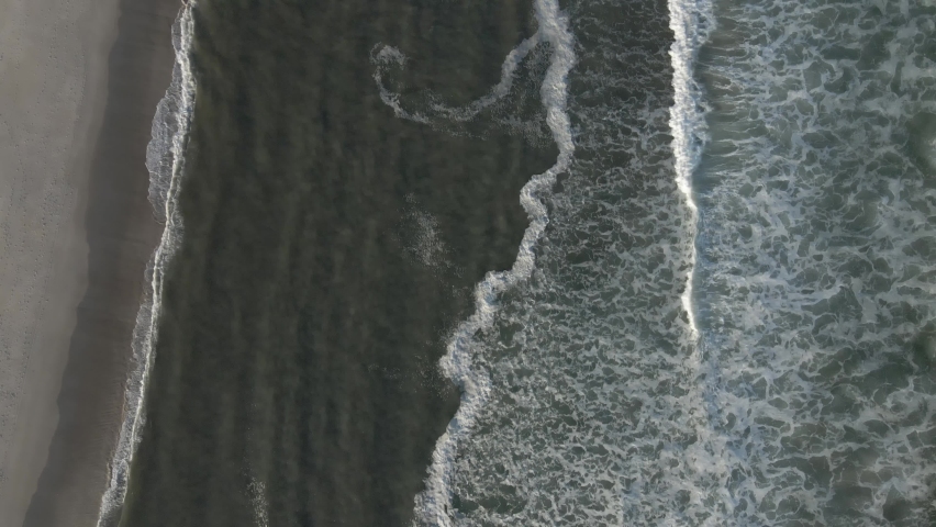 Slow Scenic Atlantic Ocean Surf Waves Washing Coastline During Sunset In Summertime At Long Beach Island, New Jersey. - Aerial Topdown Shot