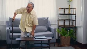 Old man grandfather with eyeglasses used a walking stick to lean the ground slowly stand up from the sofa carefully in living room at home. Asian senior old gray-haired suffering from knee pain ache - Powered by Shutterstock - Get 15% off with code: PIKWIZARD15