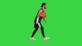 Wide shot. Side view. Young basketball player dribbling the ball while walking on a Green Screen, Chroma Key. Professional shot in 4K resolution. 068. You can use it e.g. in your medical, commercial - Powered by Shutterstock - Get 15% off with code: PIKWIZARD15