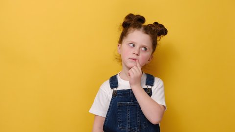 Portrait of thoughtful little girl child touch chin with finger thinking or considering, pensive lovely daughter making decision imagining idea, isolated on yellow studio background with copy space