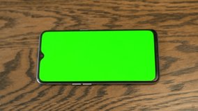 Hand Touches the Center of the Horizontal Screen of the Smartphone with a Green Screen, Green Background, Chroma Key, Mock up, Close-up. Blank. Viewing Video Content, Surfing the Internet