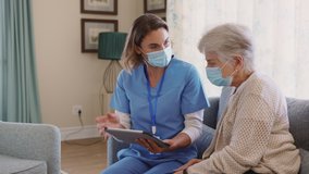 Young nurse and senior woman going through medical record on digital tablet during home visit and wearing face mask. Doctor during covid pandemic showing medical reports to old woman at nursing home.  - Powered by Shutterstock - Get 15% off with code: PIKWIZARD15