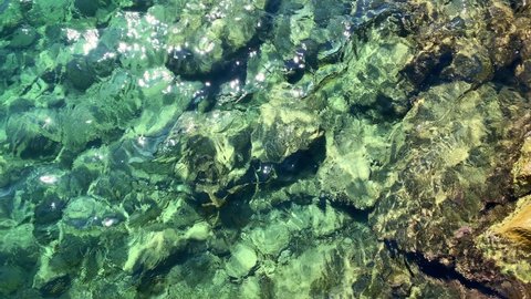Top view footage of crystal clear Aegean Mediterranean sea and rocks. It is a sunny summer day.