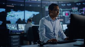 Professional IT Technical Support Specialist and Software Developer Working on Computer in Monitoring Control Room with Digital Screens with Server Data, Blockchain Network and Surveillance Maps. - Powered by Shutterstock - Get 15% off with code: PIKWIZARD15