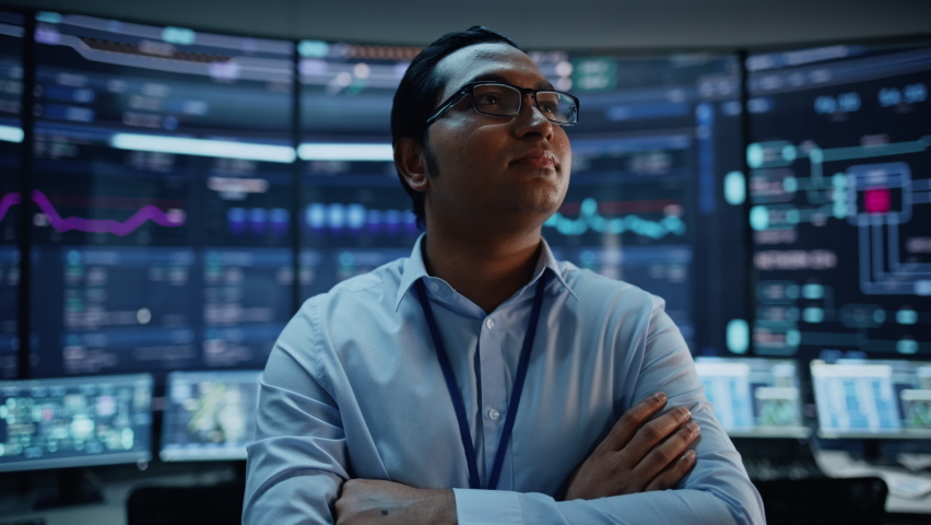 Portrait of Professional Indian IT Technical Support Specialist or Software Developer Posing in Front of Camera in a Modern Monitoring Control Room Full of Computer Displays with Technological Data. Royalty-Free Stock Footage #1069211401