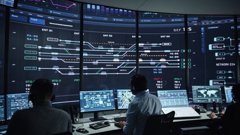 Professional IT Technical Support Specialists and Software Programmer Working on Computers in Monitoring Control Room with Digital Screens with Server Data, Blockchain Network and Surveillance Maps.