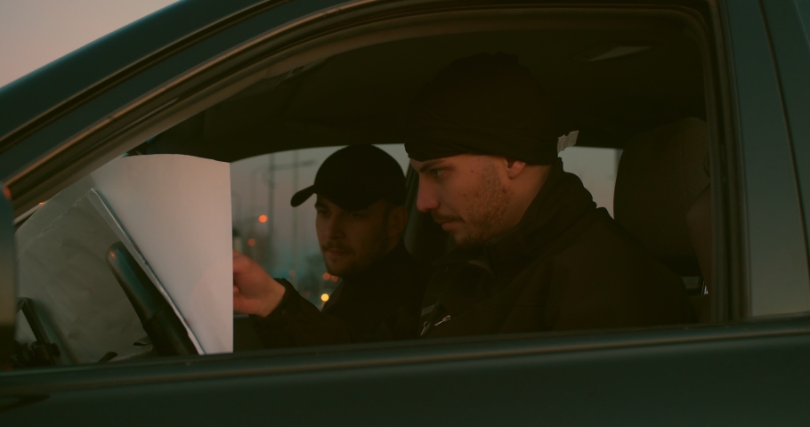 Robbers looking at a building sketch and making a plan for a heist