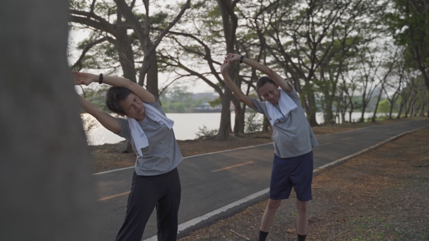 happy active senior couple exercise and stretching at park in evening sunset. smiley active asian elderly lover outdoor activity sharing good moment together. fitness duo mature workout at park.