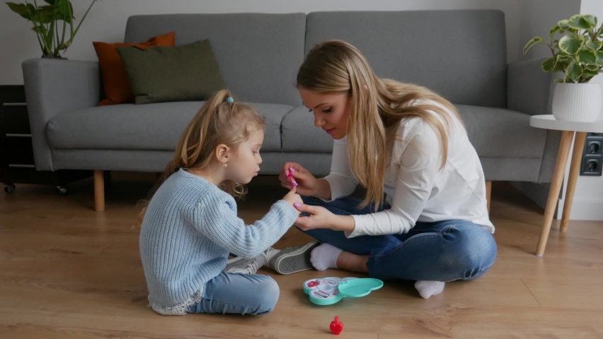 Mother and little daughter paint their nails with toy nail polish. Kid playing with mom at home. Concept of good parenting and happy childhood, family leisure Royalty-Free Stock Footage #1069215736