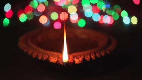 A beautiful Handmade Designer Clay Oil Lamp with a burning cotton wick having colorful lights bokeh in the background. 